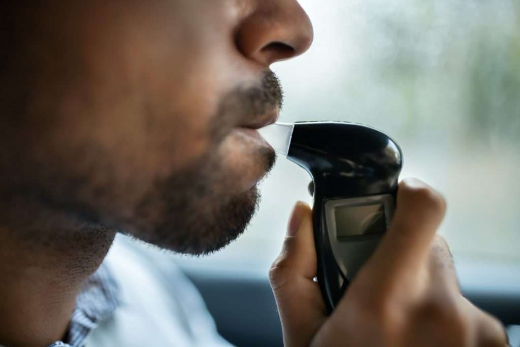 man being tested for alchachol man blowing into a breathalyser