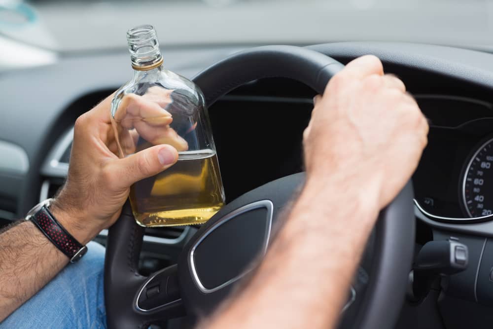 A Man Drinking Alcohol While Driving His Car Photo of a Man Drinking Alcohol While Driving His Car
